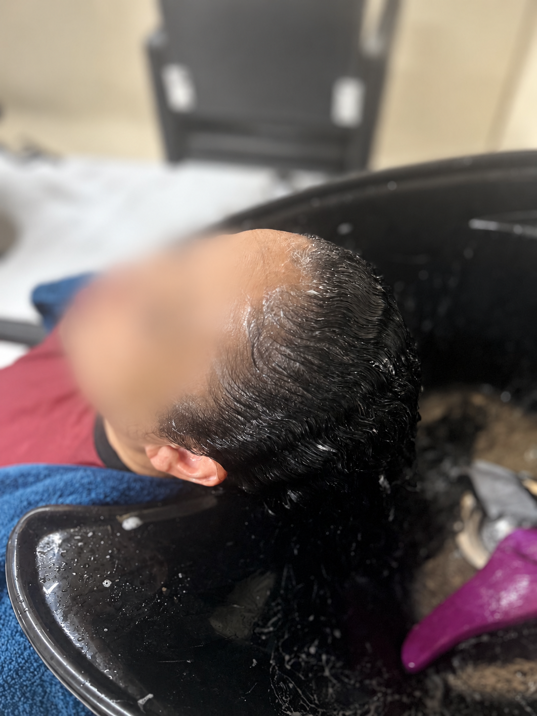 Hair washing at the salon basin, client face blurred
